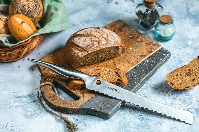 Хлебный нож с волнистым лезвием на фоне хлеба